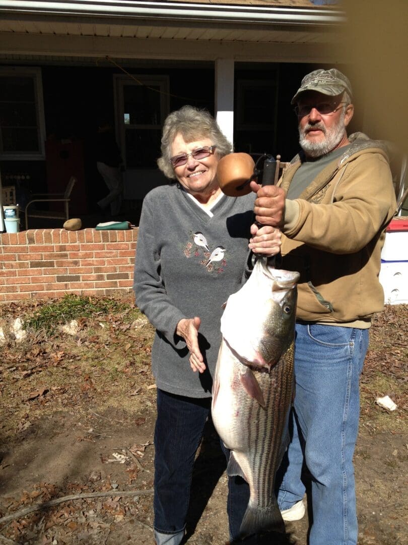 A man and woman holding up a striped bass.